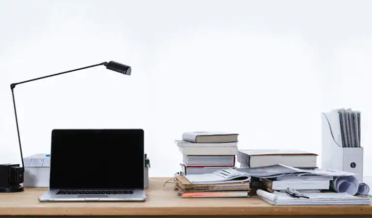 Laptop on a busy desk full of files