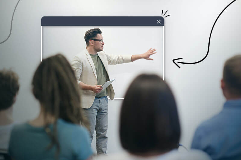 white man talking to group of people while pointing at white board