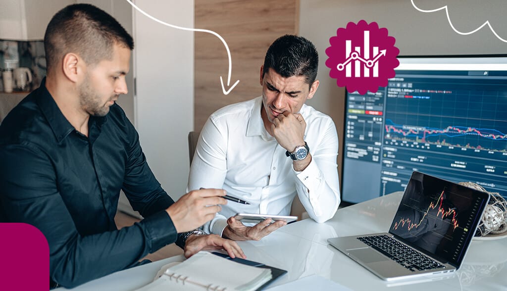 two men sitting at desk in front of laptop